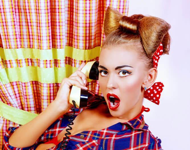 Surprised pinup girl with a hair bow bun, using an old telephone