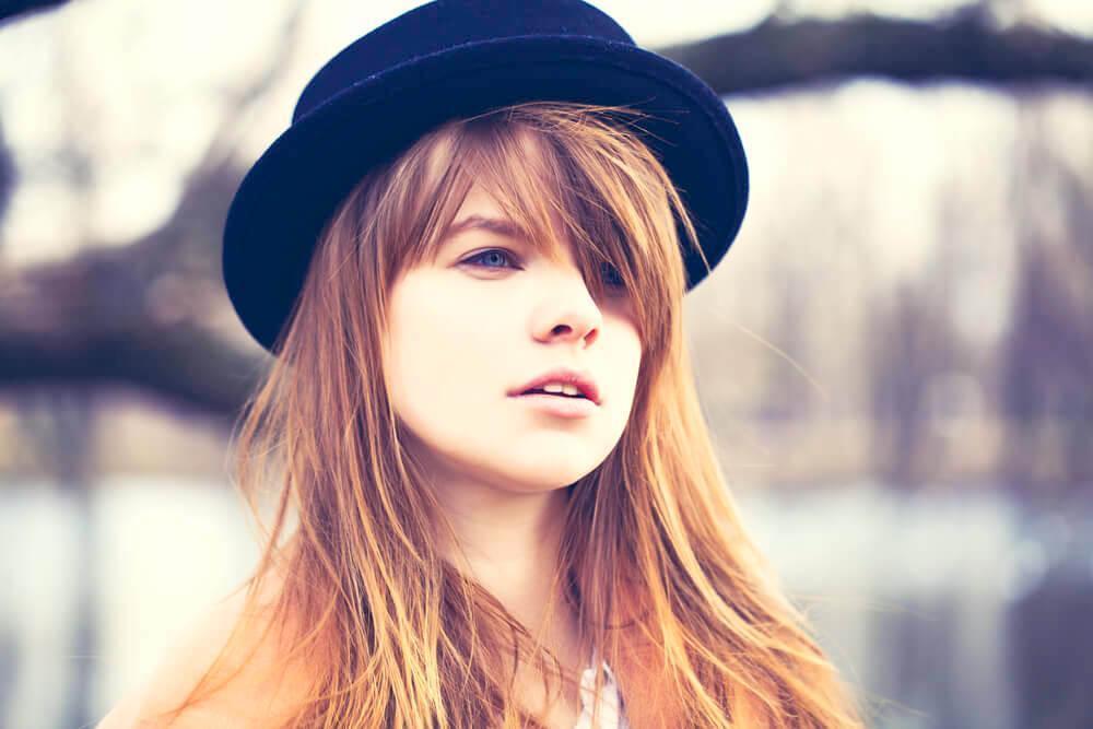 Simple pretty young woman with long hair bangs wearing a black hat - fun hairstyles