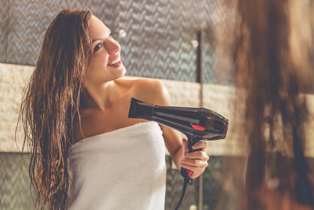 Woman in towel blow drying hair