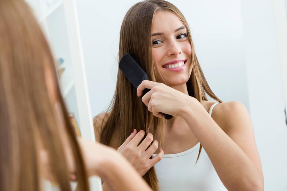 Woman Brushing Hair in Front of Mirror
