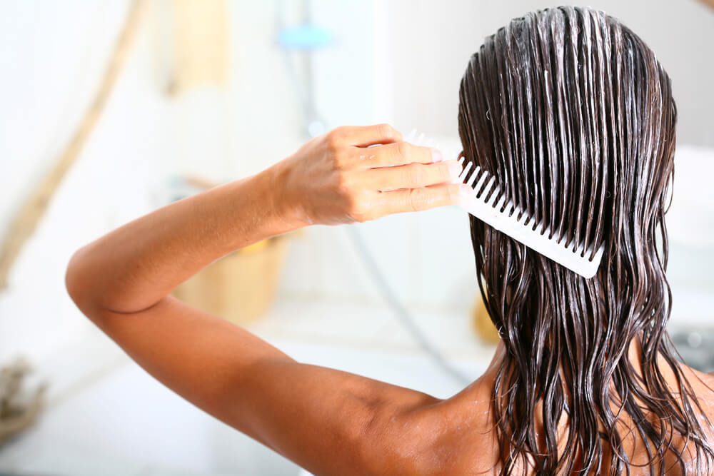 Woman combing conditioner through hair