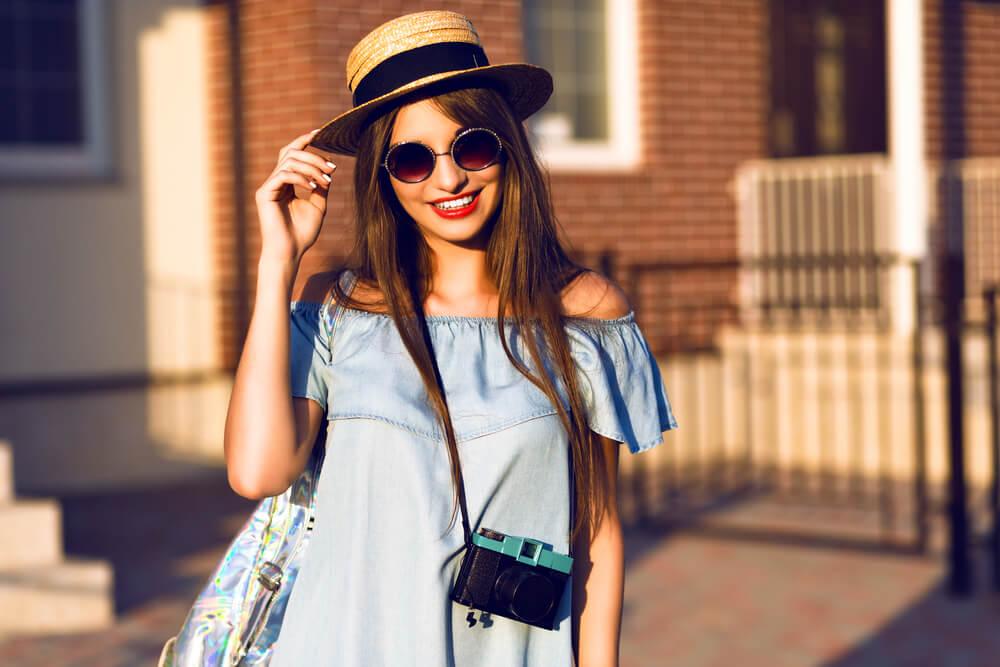 woman with camera and sunhat smiling in the sun