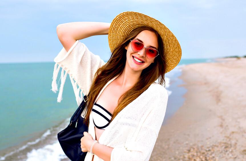 woman with wide-brimmed hat and large bag on the beach