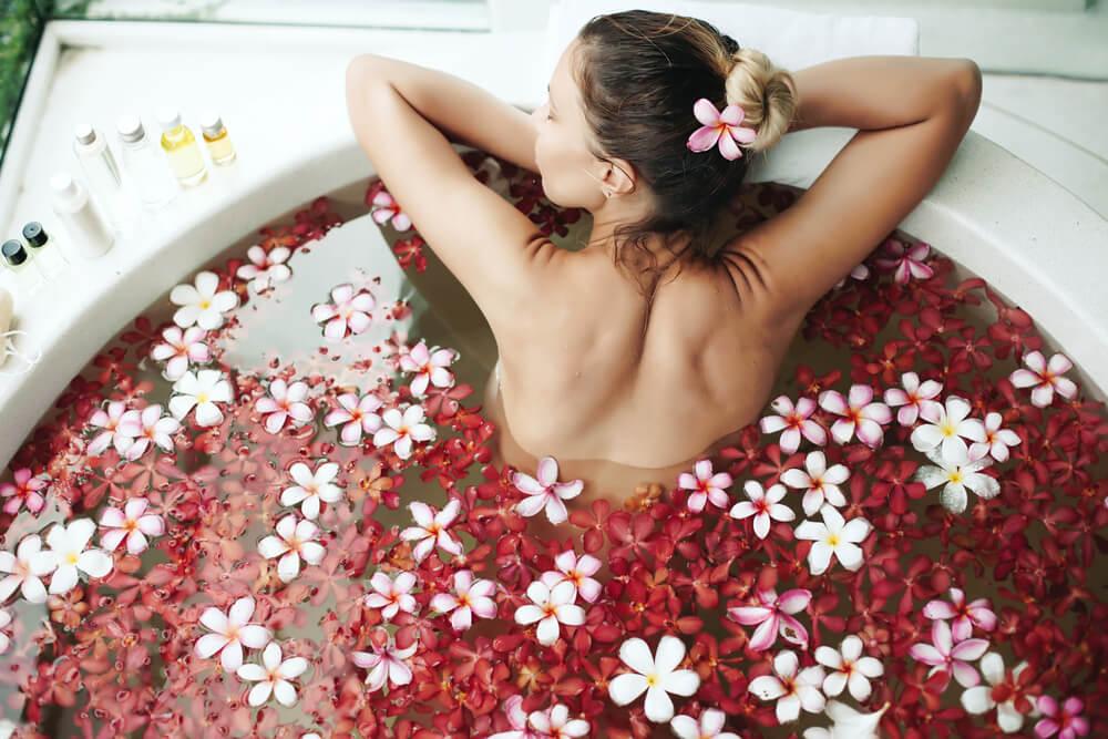 woman relaxing in geranium-filled bathtub