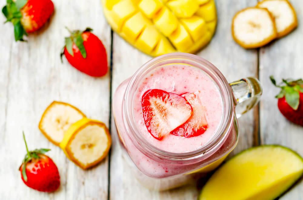 Strawberry, banana and mango smoothie on white wood