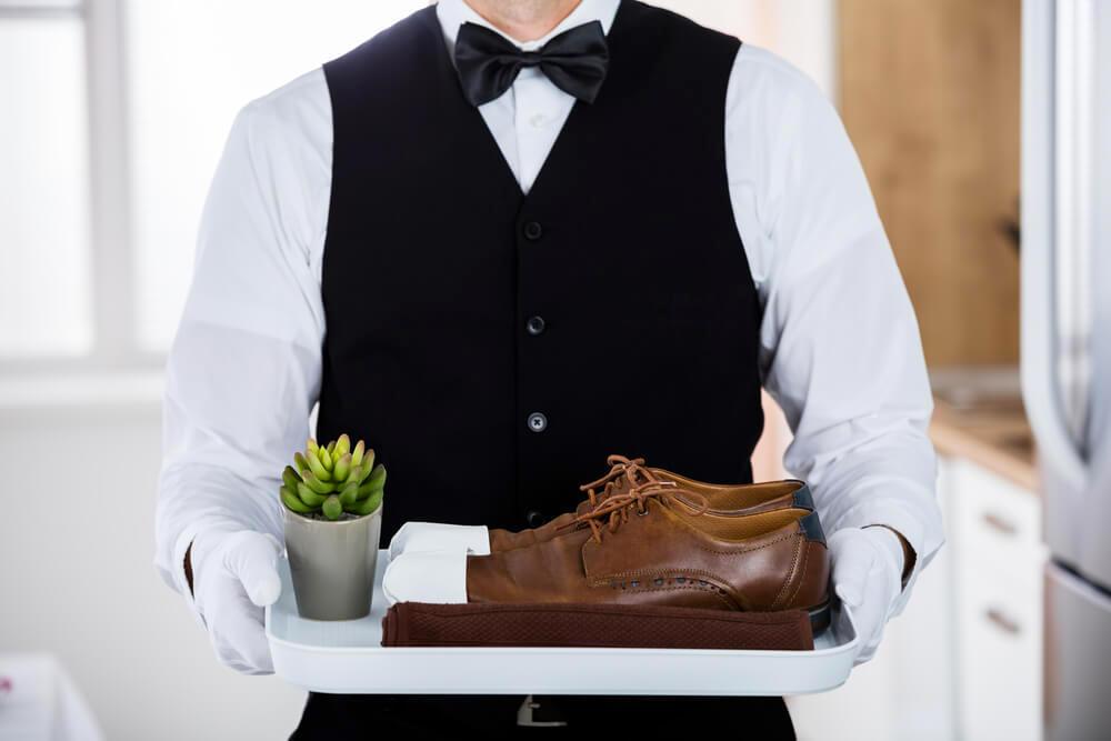 Butler presenting leather shoes on a plate