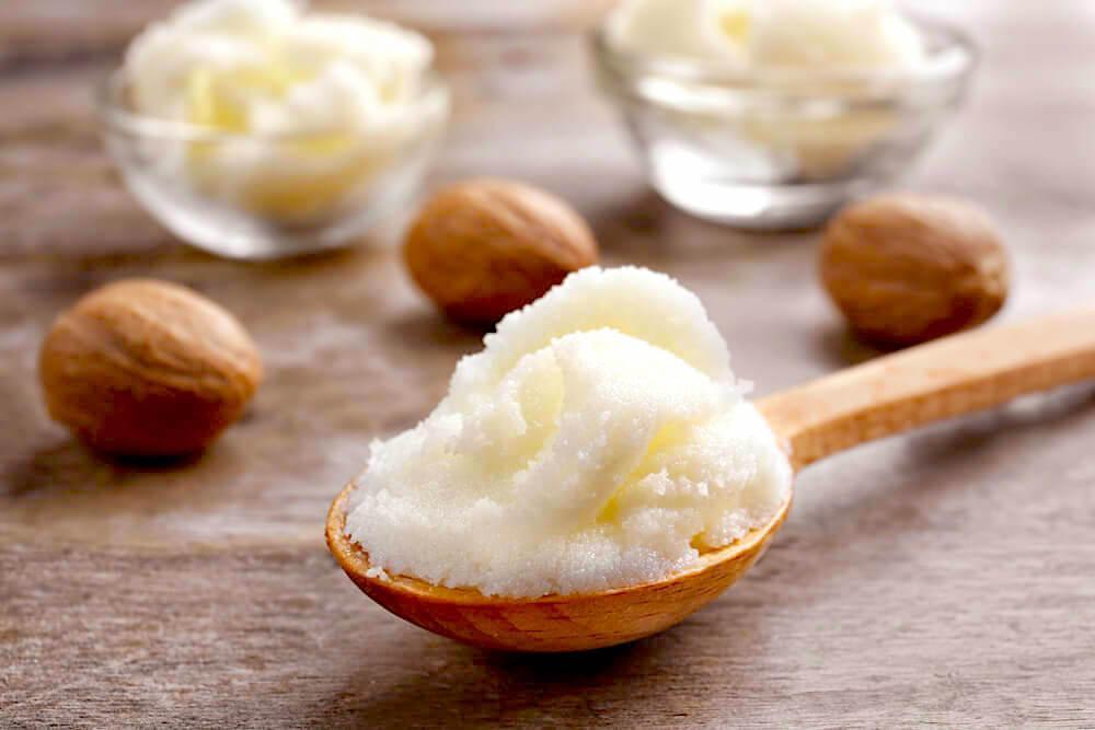 Spoonful of butter surrounded by Shea nuts