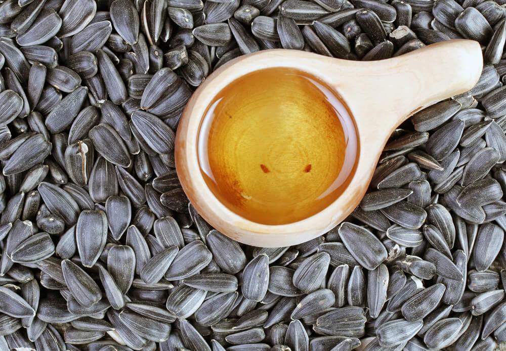 Spoonful of oil surrounded by sunflower seeds