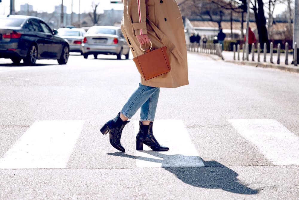 Unknown woman in trench coat, denim jeans and ankle boots
