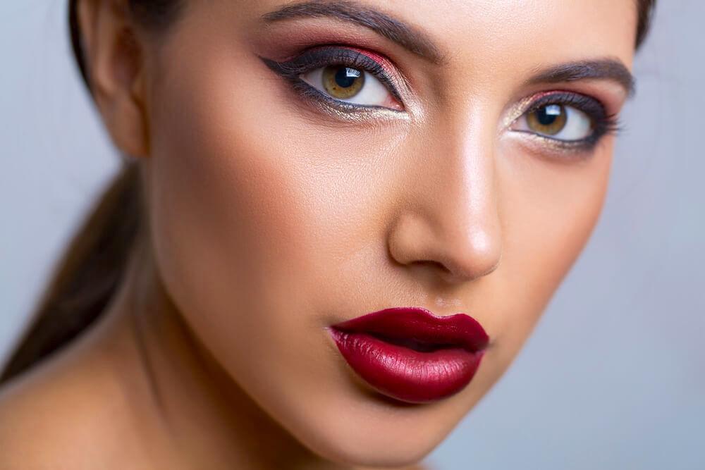 Beautiful woman with deep berry lipstick and bright eye makeup