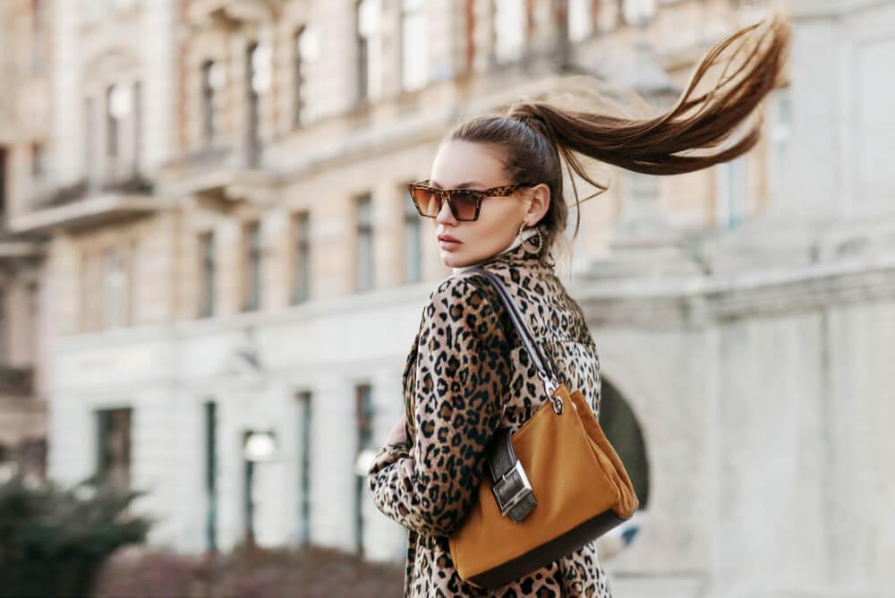 Woman in animal print coat and beige bag