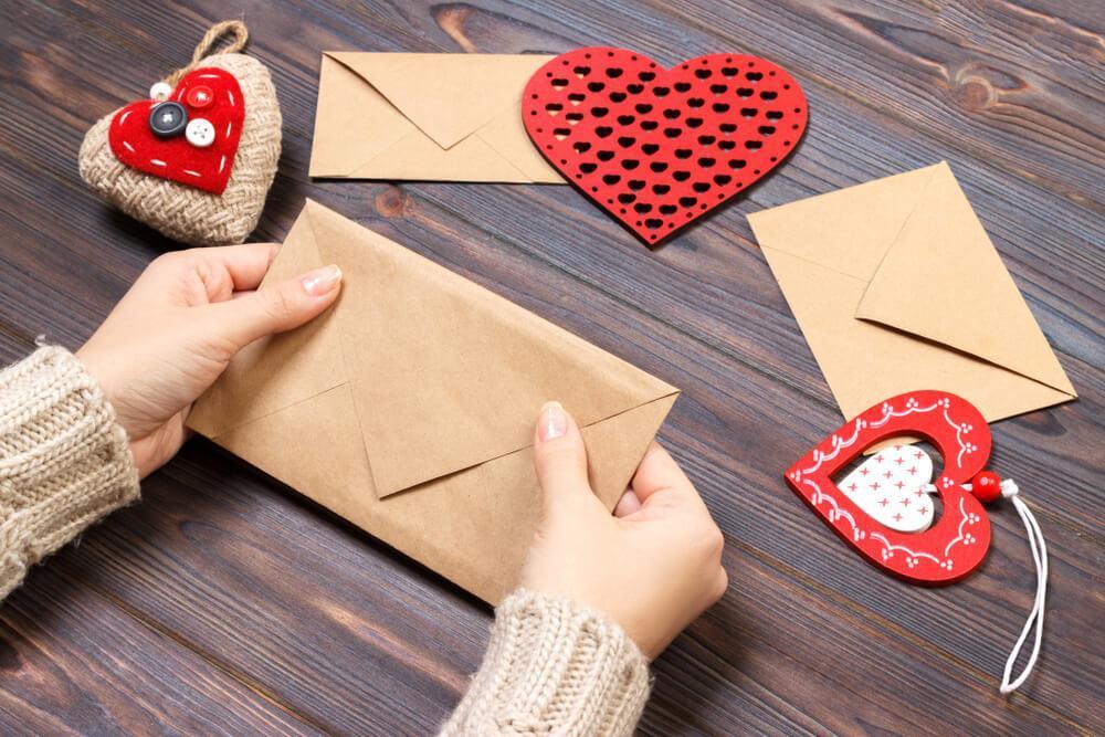 Preparing Valentine's Day greeting cards in envelope 
