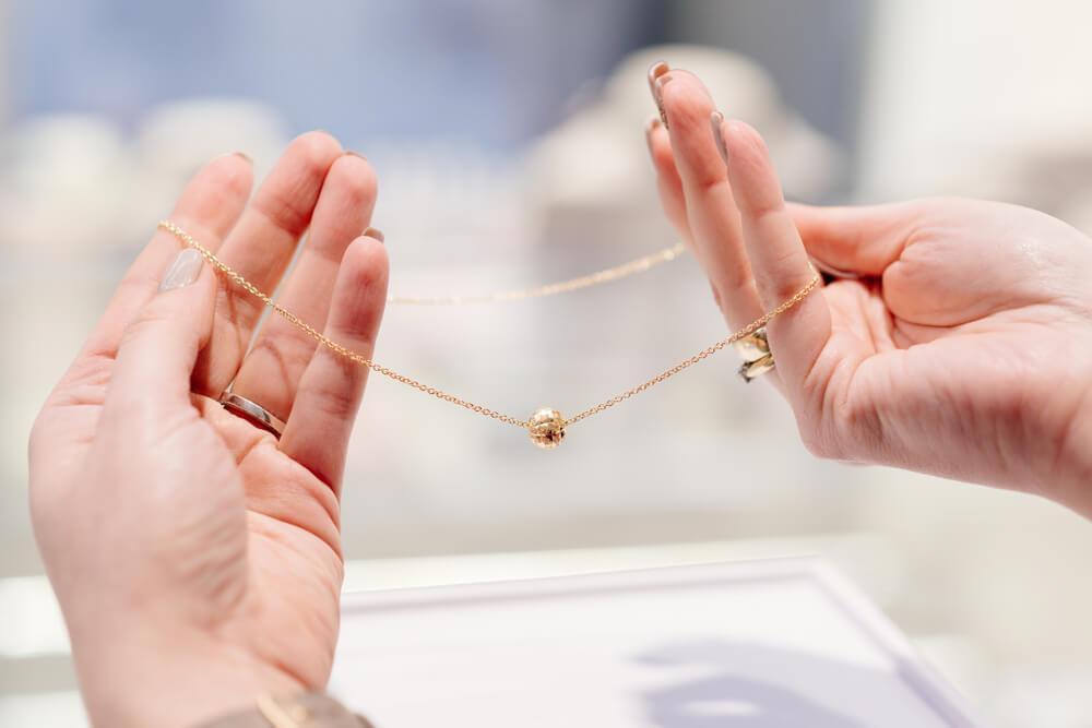 Female hands holding up a delicate necklace 