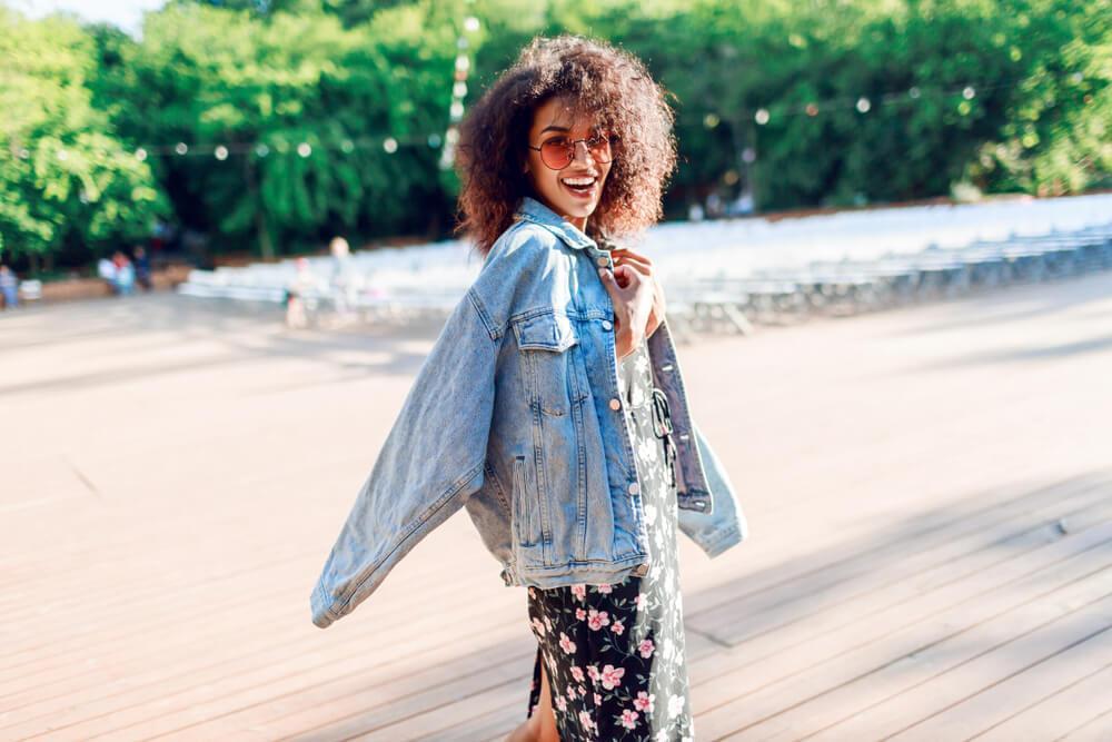 Happy smiling woman with denim jacket on the beach