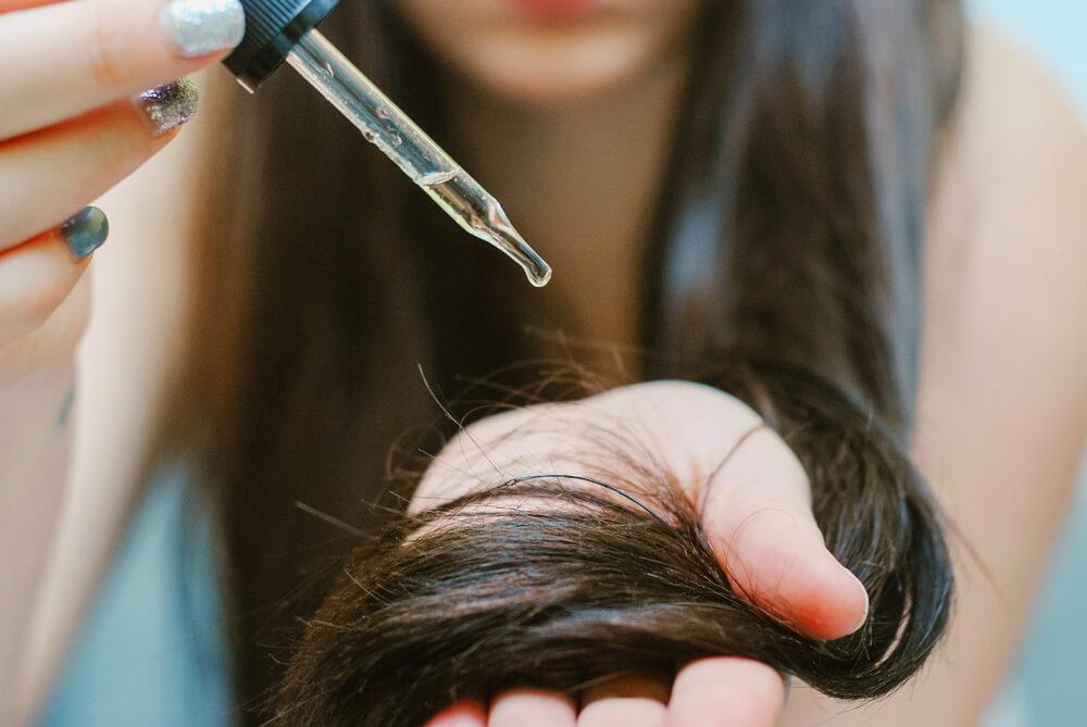 Woman applying hair serum to ends of her hair