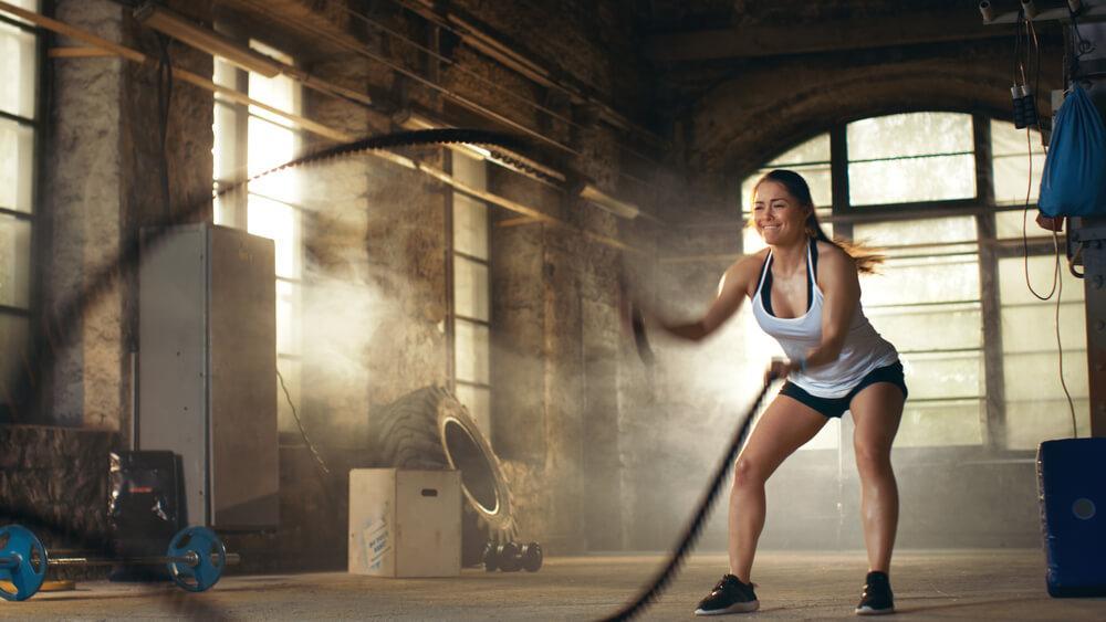 Woman working out in the gym using thick rope 