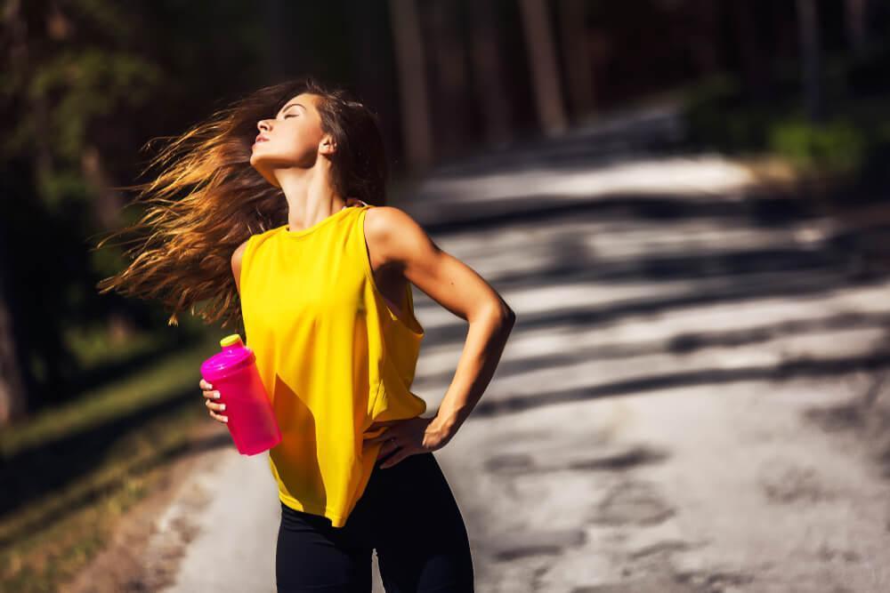 Athletic woman flipping her hair while holding water bottle