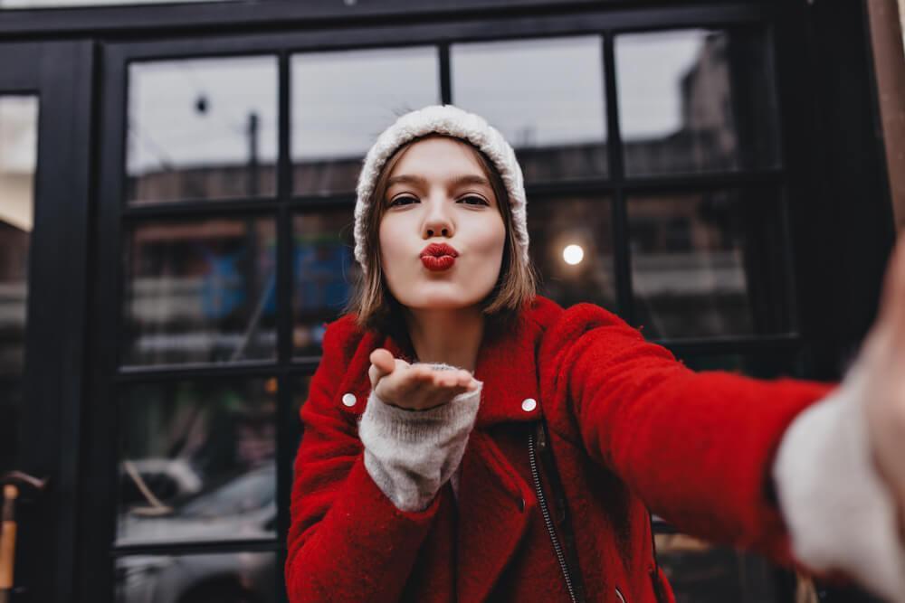 Woman with red lipstick blowing a kiss at camera