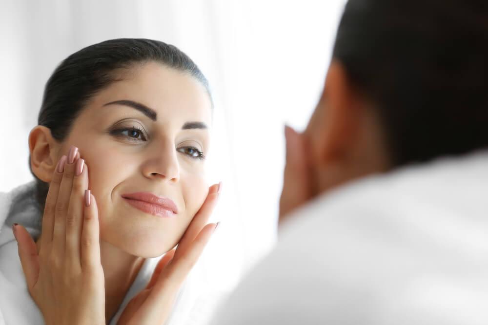 Woman looking in mirror touching her face