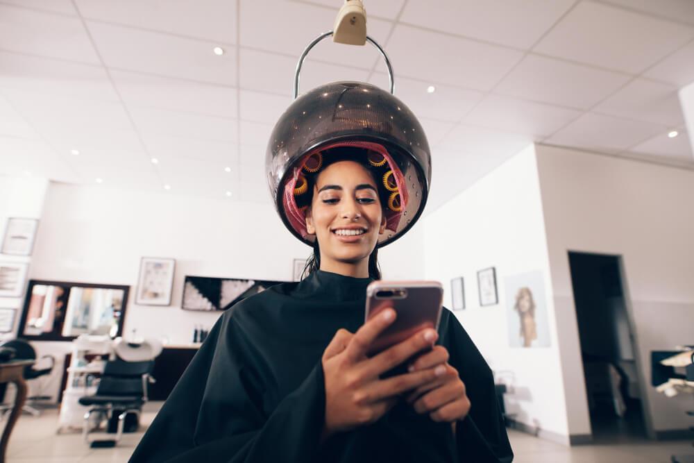 Woman sitting under hair steamer with curlers in her hair