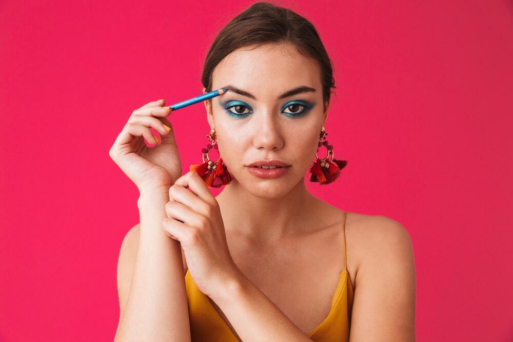 Woman with blue eyeshadow and eyeliner pencil