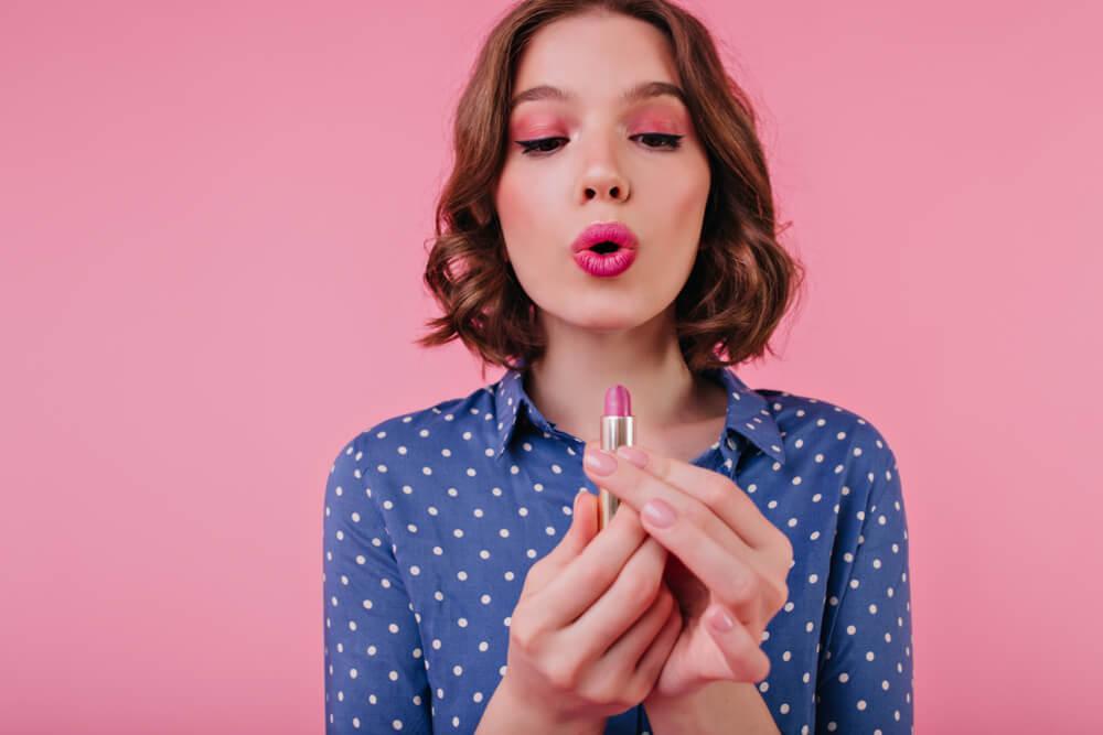 Woman with blush applying lipstick