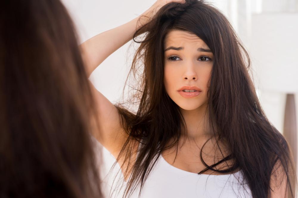 Woman looking at hair in mirror