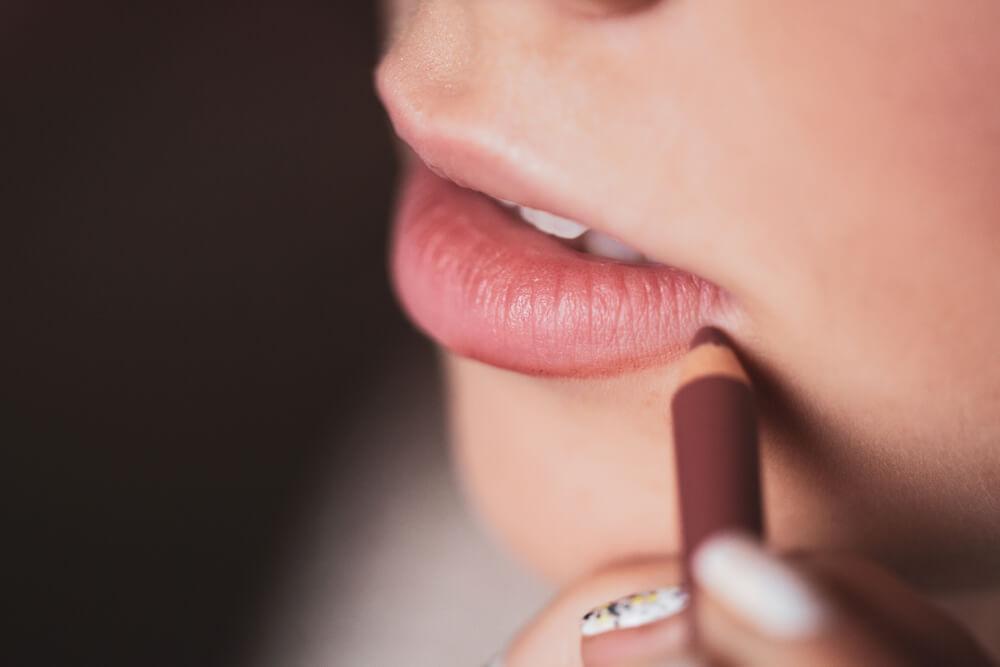 Close-up of woman applying lip liner