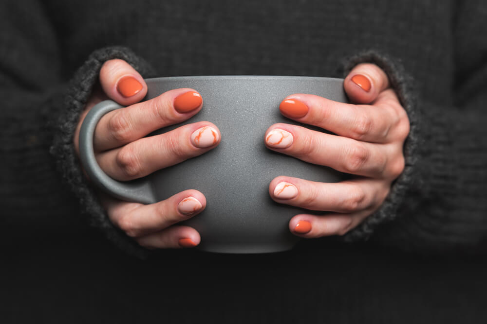 Hands holding mug with manicured nails