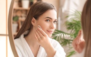 Woman applying foundation in front of mirror, trying to make sure it doesn't look flaky