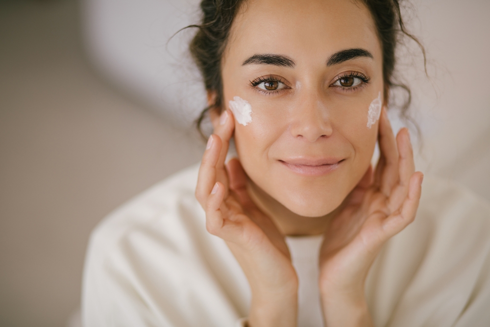 Woman applying face cream to skin
